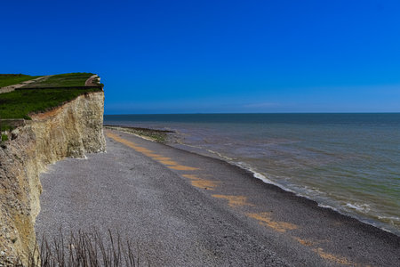 Imposing chalk cliff towering above the pebble beach with the sea extending to the horizon under a...
