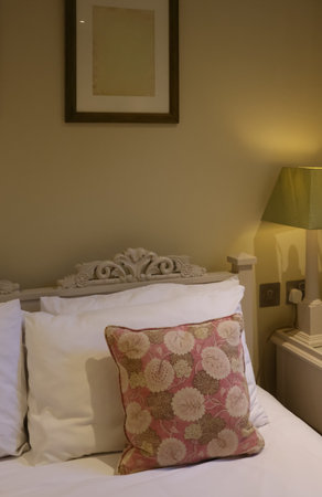 Cozy bedroom featuring decorative pillow, white bedding, and carved headboard. Cotswolds...