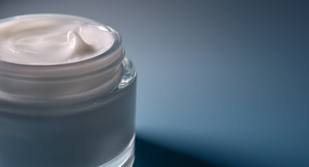 Hydrating facial cosmetic cream in a glass container, showing creamy texture and soft light, symbolizing wellness and self careの写真素材