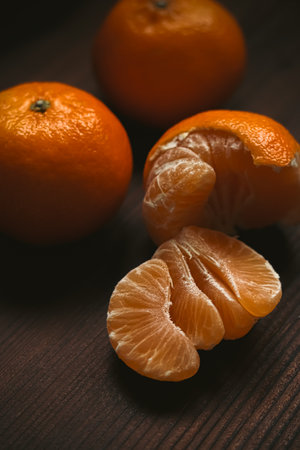 Mandarins and peeled segments presenting fresh, healthy citrus fruit on a rustic wood surface, rich in vitaminsの写真素材