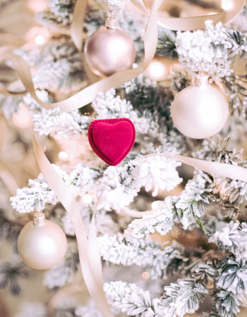 Red velvet heart shaped jewelry box among frosted branches of a festive Christmas tree with delicate ribbons and ornamentsの写真素材