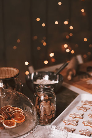 Gingerbread figures on a baking sheet and in a jar, preparing for holiday celebrations with dried oranges, cinnamon, and string lightsの写真素材