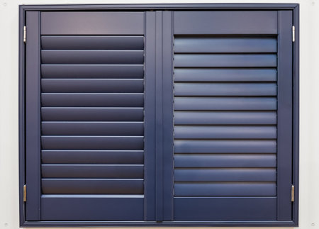Navy blue wooden window shutters for an interior home, showing closed slats for privacy and managing lightの写真素材