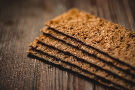 Stack of crisp rye crackers on rustic wooden background, offering a healthy and wholesome snack...