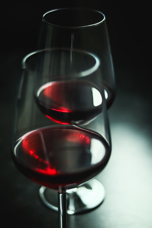 Red wine pouring into elegant glasses, creating reflections and a moody atmosphere for an evening tasting experienceの写真素材