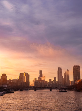 London skyline at sunset, showing buildings, bridge, river, and colorful sky. Urban scene with purple and orange lightの写真素材