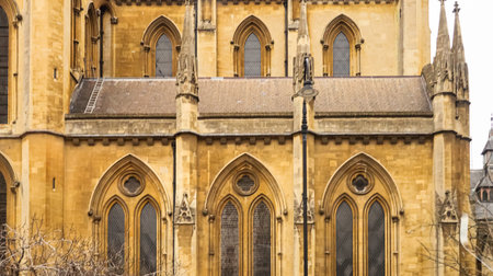 Westminster Abbey displaying detailed golden stone architecture, arched windows, and decorative elements under an overcast skyの写真素材