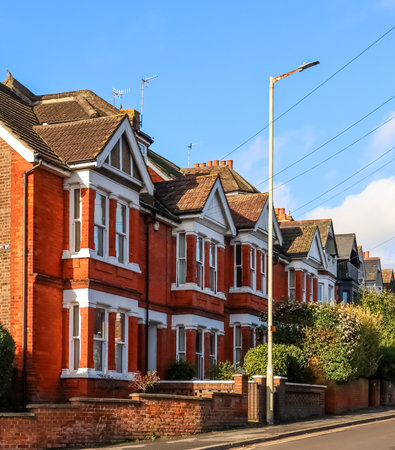 Row of traditional Victorian red brick terraced houses with white bay windows and gables under a clear blue sky in Hemel Hempsteadの写真素材