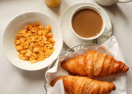 Enjoying a European style morning breakfast with coffee, golden croissants, and cereal flakes on a...