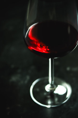 Red wine swirling inside a clear glass, showing rich color and dynamic reflections against a dark, dramatic backgroundの写真素材