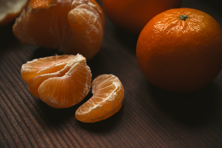 Juicy peeled mandarin segments and full mandarin fruit displaying healthy, organic citrus freshness...