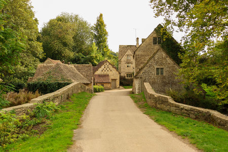Ancient stone bridge spanning a tranquil stream, connecting a pathway to charming traditional...