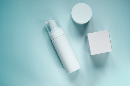 White cosmetic skincare product set featuring bottle and box on light blue background, top view providing copy spaceの写真素材