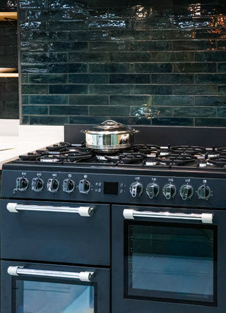Dark modern kitchen interior featuring a cooking pot on a gas range stove with stylish teal subway tile backsplash