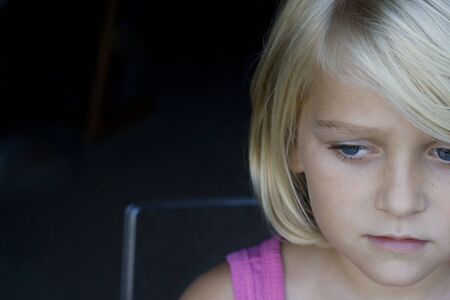 Horizontal portrait of a sad girl with blue eyes looking down. Sad feeling. Space for copy text