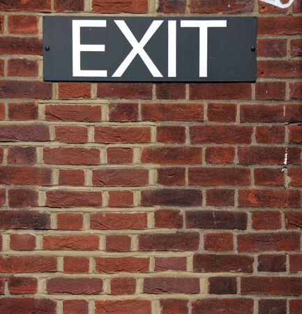 A black and white exit sign put up on a red brick wallの写真素材