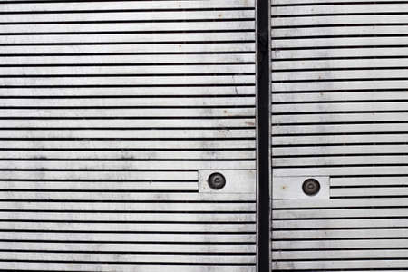 Close up of panels with horizontal slats cladding a facade with rusty screws