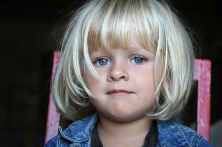A young child sitting on a chair, looking at the camera. Real peopleの写真素材