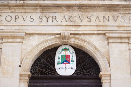 An old coat of arm on a building in Syracuse, saying servus per iesumのeditorial素材