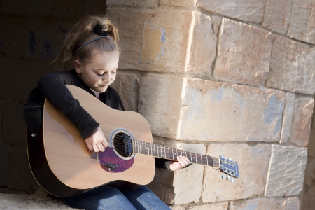 A girl learning or practicing on a musical instrument, a guitar. Space for textの写真素材