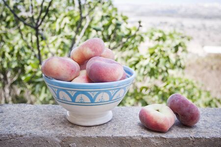 A ceramic bowl with donut peaches, so called peento, in a gardenの写真素材