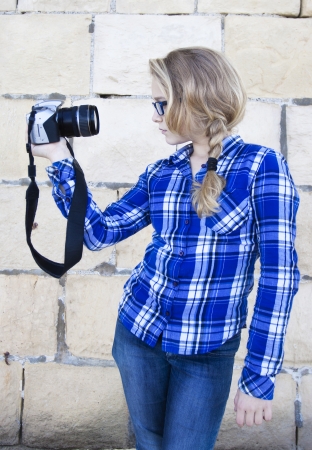 A modern youmg woman in profile holding up a digital camera, snapping a selfportraitの写真素材