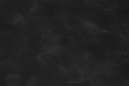 The texture of dirty scratched plastic. Abstract rectangular dark background with light blur.