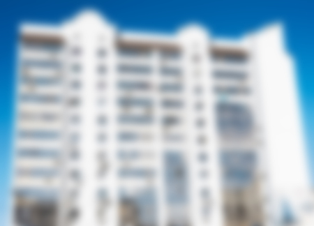 Blurred horizontal background with multi-storey building against the sky.