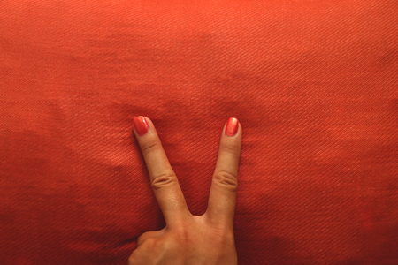 V Sign Manicure  Hand with Orange Nail Polish on Matching Pillow - Retro Backgroundの写真素材