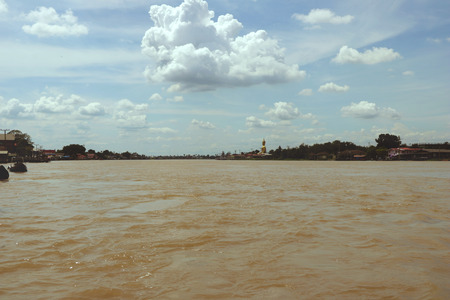 Cloudy Sky over Muddy River with Golden Buddha Statue - Chao Phraya River Thailandの写真素材