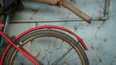 Vintage Old Red Bike on Rough Painted Blue Wall with Rustic Logs/ Dry Tree Branches - Abandoned Garden/ Junkyard. Countryside Thailand.の写真素材