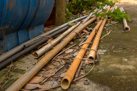 Vintage Old PVC Water Pipes on Dirty Concrete Ground - Outdoor Garden/ Dry Leaf/ Dirty Moldy Groundの写真素材