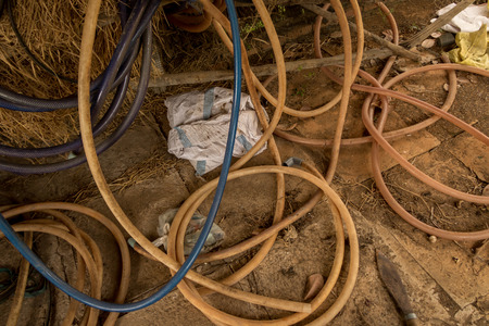 Vintage Old Hosepipe on Dirty Concrete Ground - Abandoned Chicken Coop. Messy Toolsの写真素材