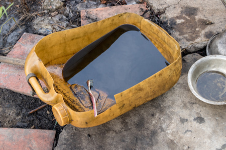 Used Gray Diesel Oil Bottle with no Label - Dirty Greasy Aluminum Bowl on Old Concrete Ground. Outdoor Junk Yardの写真素材