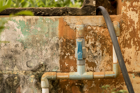 Dirty Old PVC Valve/ Plastic Water Pipeline - Vintage Moldy Wall Texture. Abandoned Garden. Yellow Warm Toneの写真素材