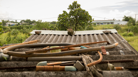Water Supply Junk on Dirty Old Corrugated Roof - Concrete Texture. Green Gardenの写真素材
