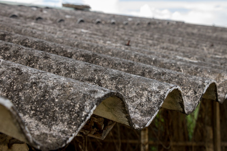 Dirty Moldy Corrugated Roof of Abandoned Asian Chicken Coop with Rusty Wire Fence - Blue Bright Sky with Cloudsの写真素材
