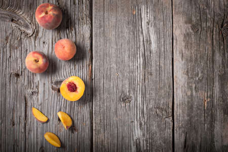Flat lay view of whole and sliced peaches on weathered barn wood with generous copy space.の写真素材