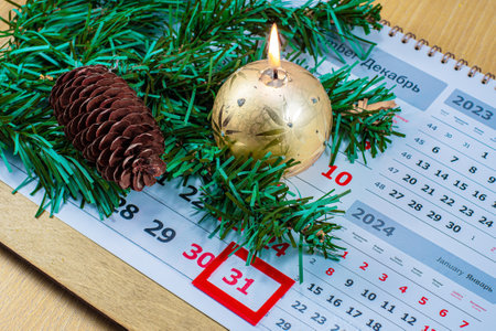 New Year. Fir branch with a pine cone and a burning candle on a calendar sheetの写真素材