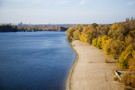 View of the river with the beach and yellow treesの写真素材