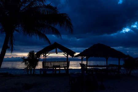 View of the late sunset through the houses on the beach. The palms. House. Beach.の写真素材
