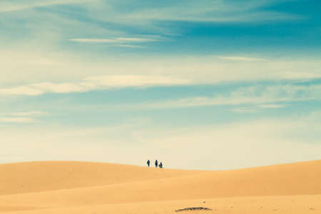 Group people in the distance walk on top of a hill in the desert.の写真素材