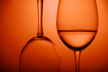 close-up two wine glasses on orange background. Horizontal. One glass upside down.の写真素材