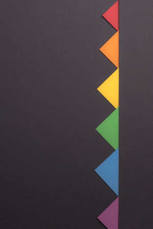 Minimalistic colored triangles on Minimalist Black background, copy space, vertical orientation.