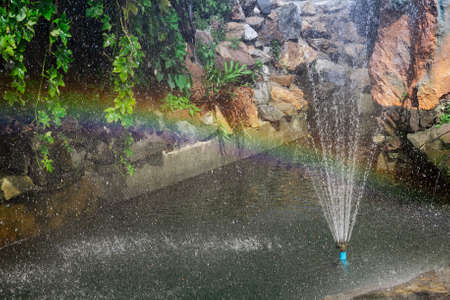 Rainbow from the fountain in a decorative small pond, a symbol of happiness.の写真素材