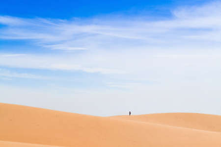 In the distance, on the crest of the dune is a silhouette of a man.の写真素材