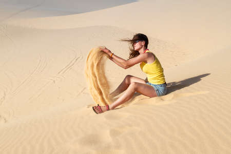 Woman playing with sand in the desertの写真素材