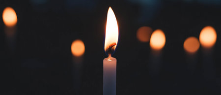 Flickering candle flame against a black background creates a warm and gentle ambianceの写真素材