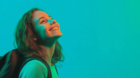 Joyful young woman smiling in colorful light with backpackの素材