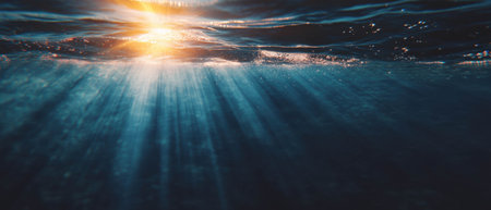 Sun rays illuminate calm ocean waters at sunrise creating a serene atmosphereの素材